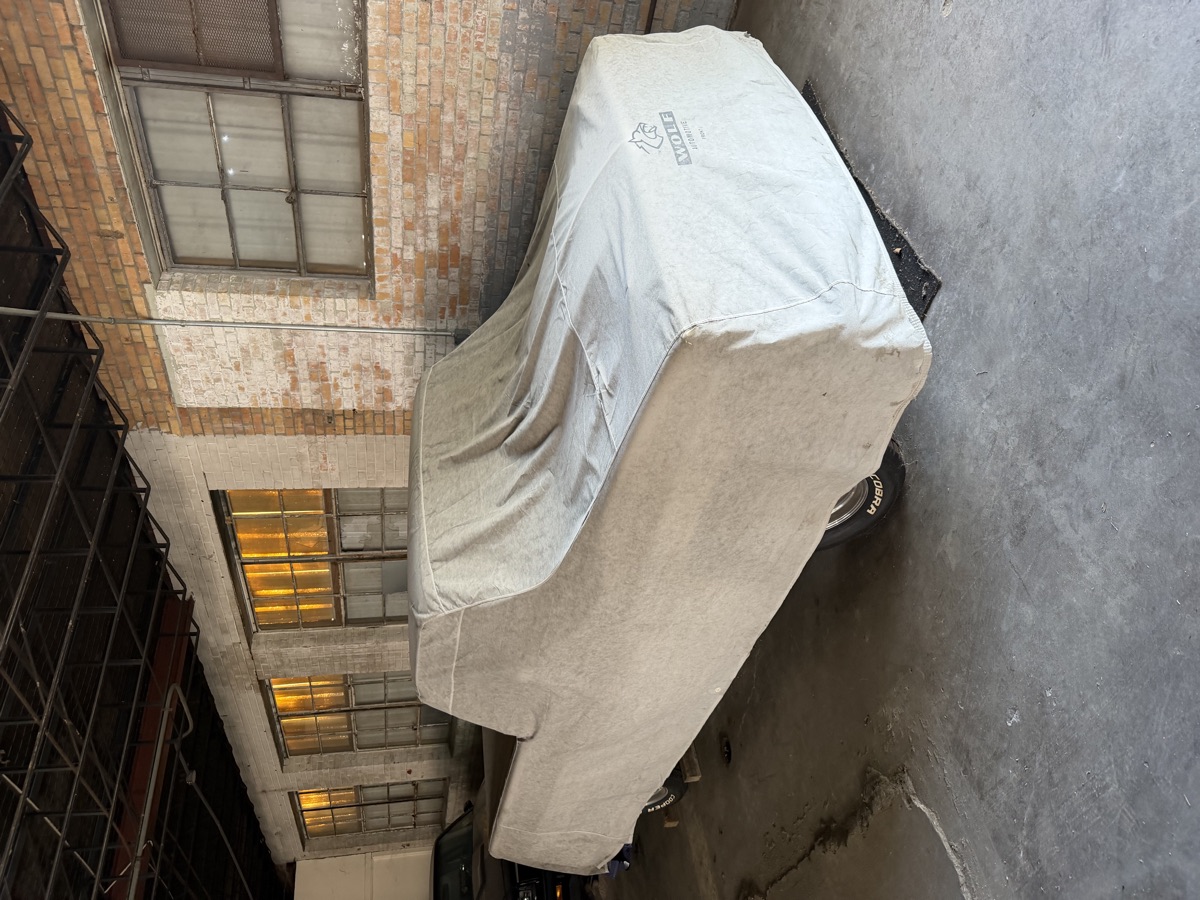 Classic truck under a fitted cover in the Bollinger garage
